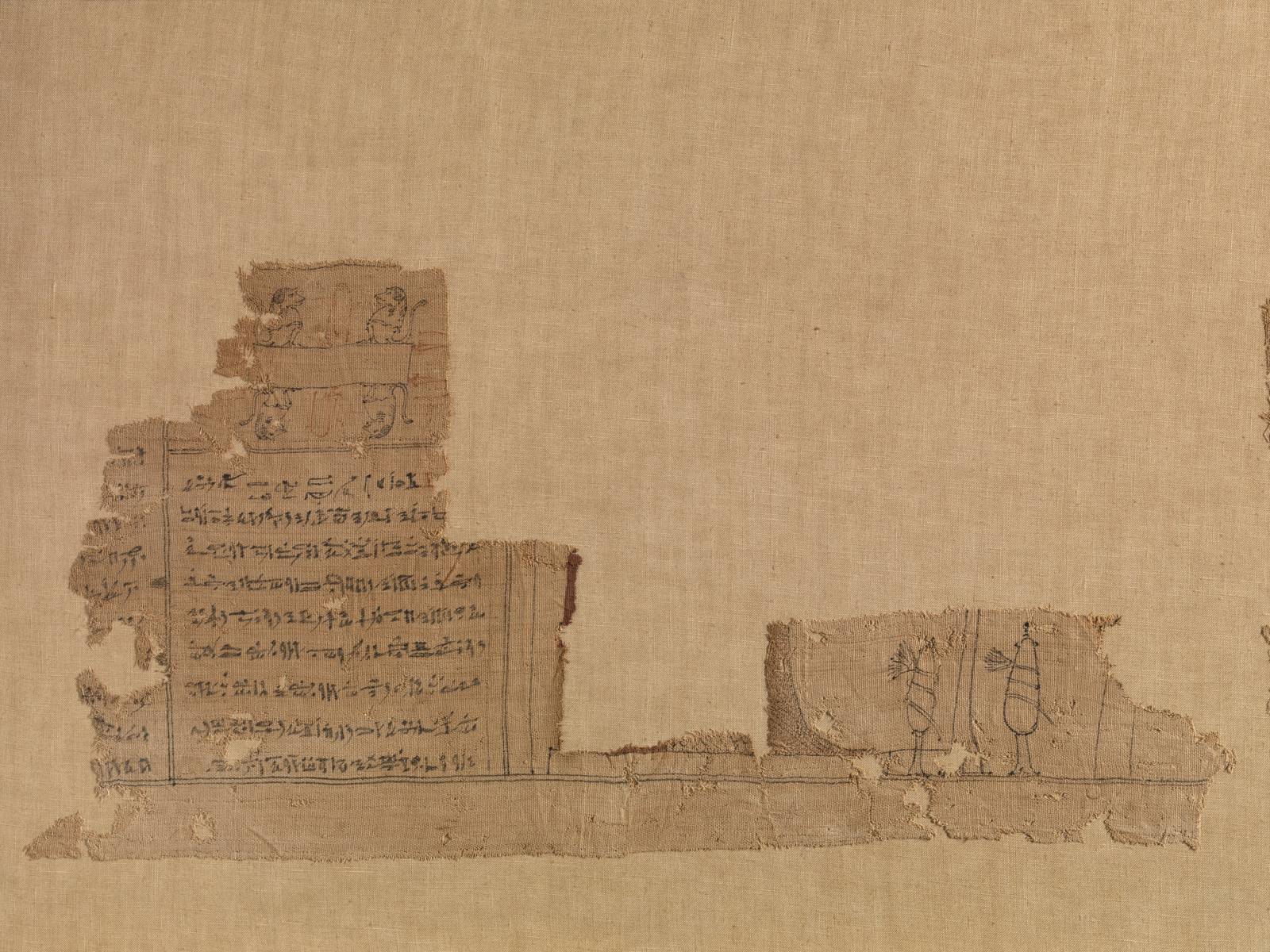 Linnenfragment met hiërogliefen en twee kleine getekende figuurtjes.